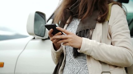 Woman using gps navigation on the smart phone near the car on the road