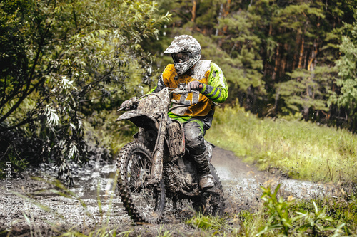 Fototapeta na szkło brudny motocykl wyścigowy Enduro jedzie przez kałużę w lesie