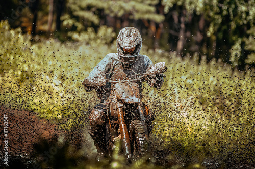 Fototapeta na szkło ekstremalne zawody motocrossowe: zawodnik biegający przez kałużę błota