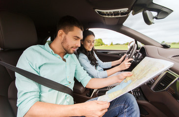 Wall Mural - happy man and woman with road map driving in car