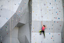 Beautiful Young Woman Starts To Climbing Big Artificial Wall