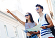 © Tijana - Two young tourists sightseeing a city, holding a map, pointing with finger