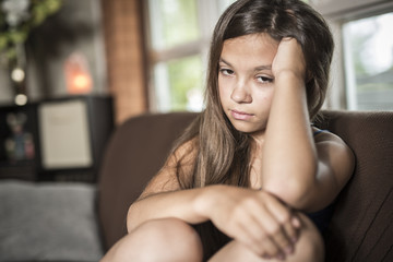 sadness teen girl sits on sofa at home