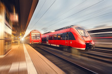 Modern High Speed Red Passenger Trains At Sunset. Railway Station In Nuremberg, Germany. Railroad With Motion Blur Effect. Industrial Concept Landscape