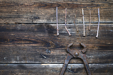 Wall Mural - old rusty tongs with nails on wooden boards background