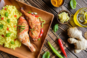 Wall Mural - Baked chicken thighs with honey, grated ginger and rice with turmeric on a wooden background