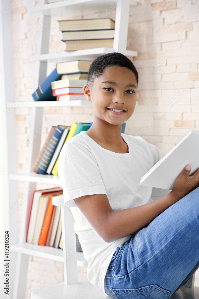 African American boy reading books in stylish library