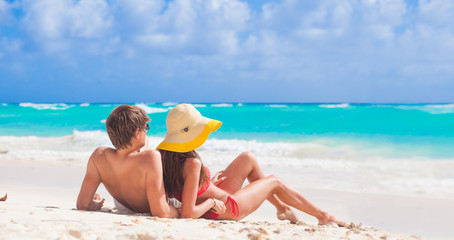 Wall Mural - back view of couple sitting on a tropical beach in Barbados