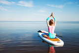 Fototapeta Konie - Woman doing yoga on sup board with paddle