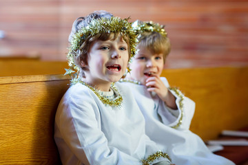 Wall Mural - Two little boys playing an angel of Christmas story in church