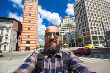 cheerful bearded man with a backpack makes selfie on the city ba