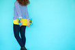 © kegfire - Back view of funky woman skater with her yellow skateboard