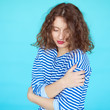 © kegfire - Woman in a striped shirt with eyes closed on blue background.