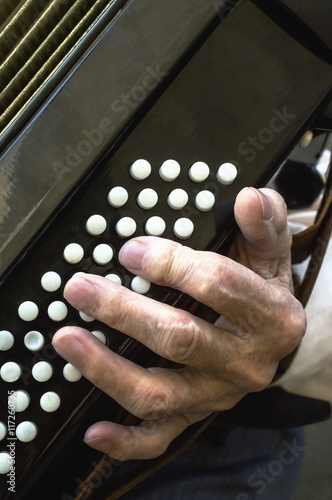 Fényképezés Details of a hand on an old accordion while playing.