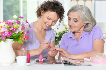 Wall Mural - Senior woman with daughter  with nail polish