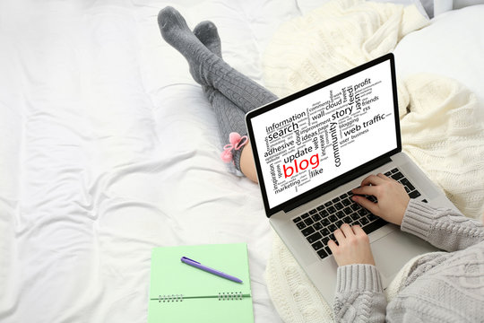 Woman using laptop on her bed. Blog concept
