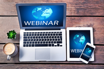 Different modern devices with cup of coffee on wooden table. Webinar concept