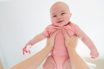 happy infant baby girl being held up in the air