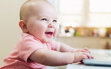 Wall Mural - Happy baby girl using laptop computer