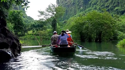 a boat trip through trang an eco tourism complex in ninh binh, vietnam.