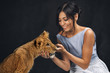 Beautiful girl playing with a lion cub on a black background