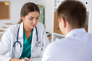 Female doctor  writing prescriptionto her male colleague or pati