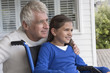 © onoky - Happy senior man with his granddaughter in wheelchair on porch