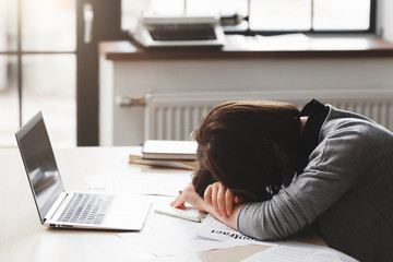 Young tired woman sleeping at office desk. Sleep deprivation, overworking, insomnia and stressful life concept