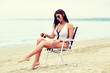 © Syda Productions - woman sunbathing and spraying sunscreen on beach