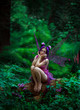 © kharchenkoirina - Fantastic photo shoot with smoke. Fairy Coquette sad tree. Background fairy forest, vines and trees. Unusual fabulous views, purple dress and torn wings. Fashionable toning.