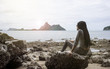 © ittoilmatar - young asian woman sitting on a rock near the sea,looked to the sea,chill out of summer,rest time,light and flare effect added,wait for something concept,selective focus,filtered image