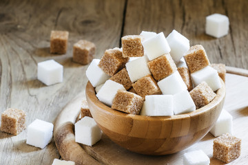 Cubes of white and brown sugar, wooden bowl, selective focus