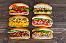 A Lot Of Big Delicious Hot Dogs With Sauce And Vegetables On Wooden Background. Their Assorted Hot Dogs To Gourmet. View From Above.
