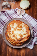 Stack of potato pancakes on a wooden table. In the background po