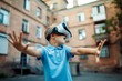 Fascinated little boy using VR virtual reality goggles. outdoor