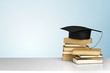 books and mortarboard on wooden table