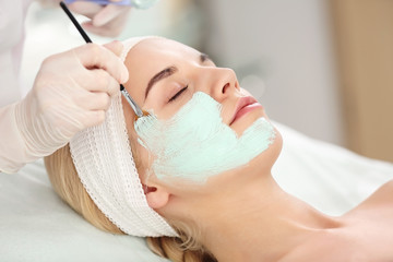 Cosmetologist applying facial mask in beauty salon