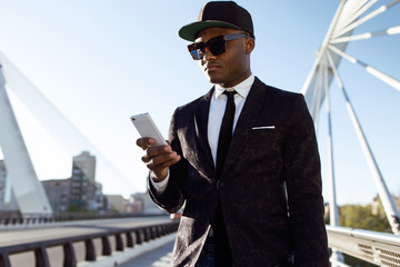 Handsome young black man using his mobile phone in the street.