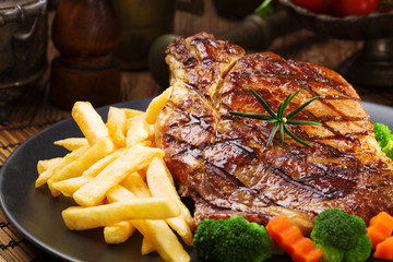 Grilled beef steak served with French fries and vegetables on a