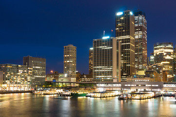 Wall Mural - Modern cityscape at night. Circular Quay skyscrapers and hotels with ferry wharfs in the evening. Sydney, Australia