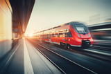 Fototapeta  - Beautiful railway station with modern red commuter train at suns