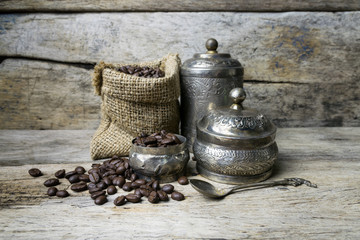 Silver cup and Coffee beans in sackcloth bag on wooden backgroun