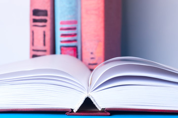 Open book, stack of colorful hardback books on light table. Back