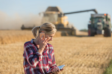 Combine harvester and tractor harvesting wheat in wheatfield