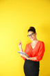© Africa Studio - Pretty young woman holding tablet on yellow background