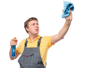 man in a overalls holds a bottle with spray and rag on a white b