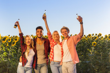 People drinking beer bottles group friends outdoor countryside sunflowers field