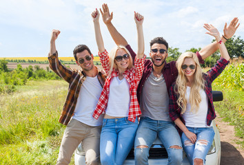 Wall Mural - excited friends on car outdoor countryside raise arms people smile holding hands up