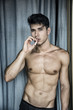 © theartofphoto - Shirtless muscular young man smoking cigarette outside, standing, front view