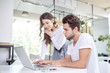 © basin_stock - Two young business people in casual wear looking at the laptop.